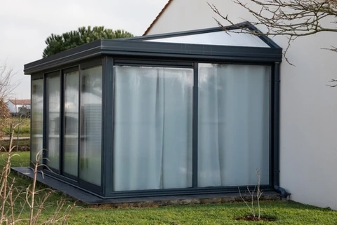 Véranda moderne attenante à maison blanche, jardin résidentiel avec pelouse