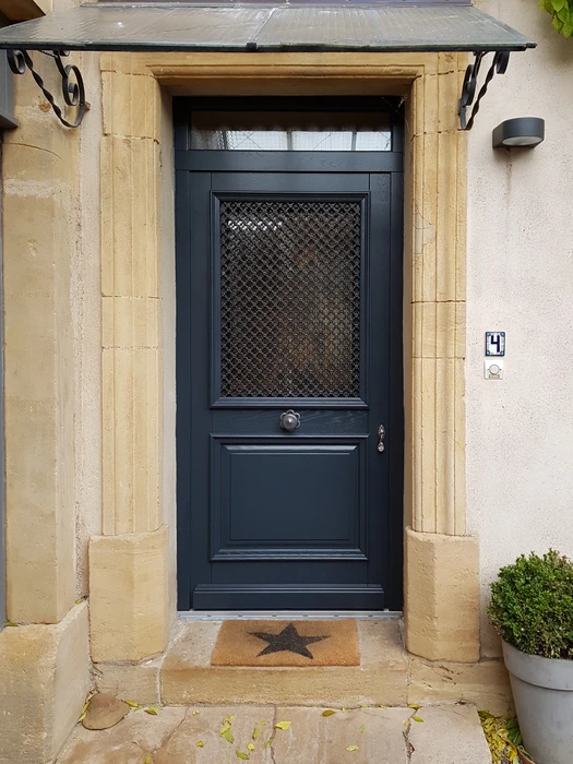 Entrée de maison élégante avec une porte d'entrée cintrée gris anthracite, vitrage transparent asymétrique à traverses courbes, poignée dorée