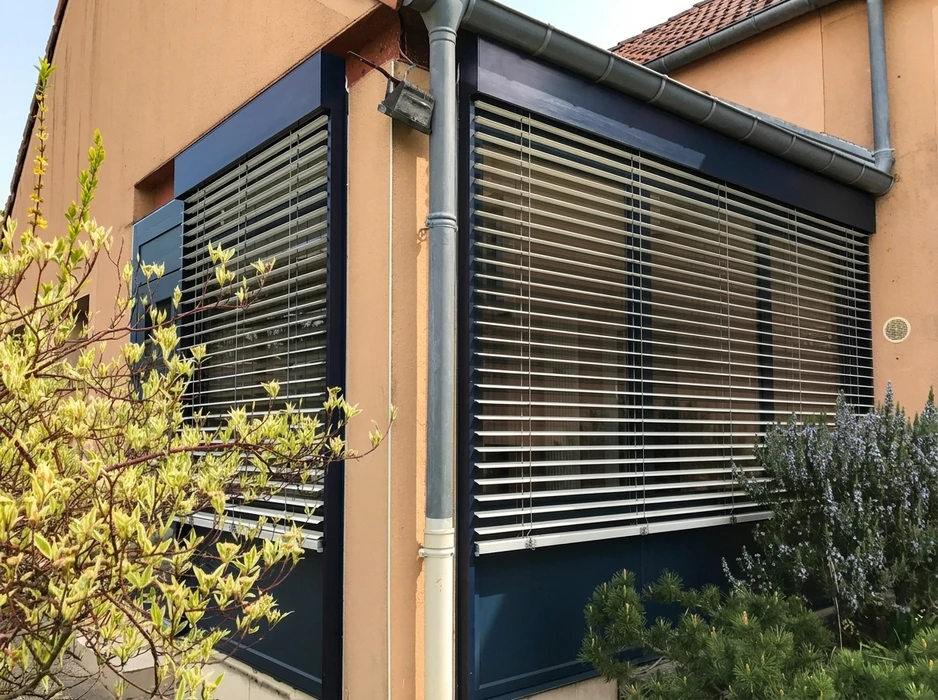 Porte d'entrée cintrée en aluminium laqué anthracite (RAL 7016), posée dans une embrasure en arc de cercle sur façade enduite