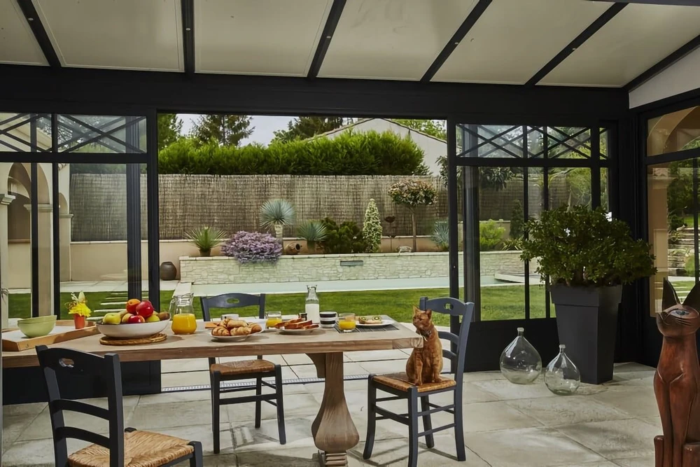 Intérieur résidentiel avec fenêtre double vantail à cadre bois donnant sur terrasse et jardin verdoyant