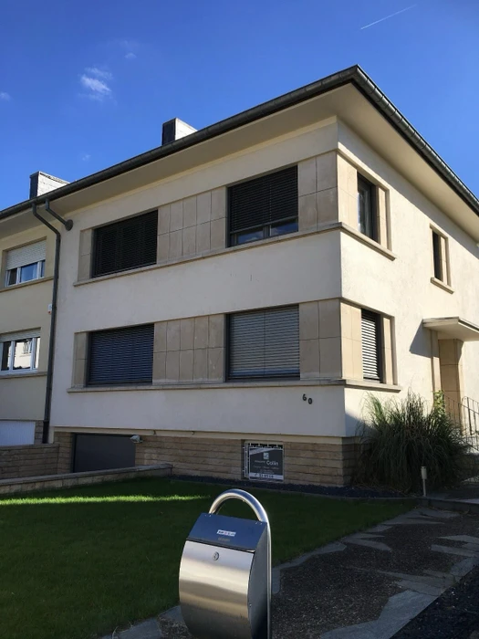 Façade extérieure d'une maison contemporaine avec volets orientables aluminium anthracite enveloppant un angle vitré