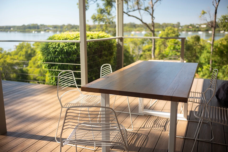 Une terrasse ensoleillée (exposition plein sud ou ouest) équipée d'un store banne en toile ou d'une pergola bioclimatique en aluminium, créant une zone d'ombre fraîche. La scène montre l'espace extérieur aménagé et ombragé, avec du mobilier confortable (chaises, table basse), illustrant le confort et la fraîcheur créés par la protection solaire. La photo est prise de jour, en conditions d'ensoleillement fort, montrant le contraste entre la zone protégée (ombragée et fraîche) et l'espace ensoleillé au-delà.