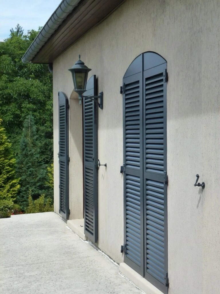 Façade de maison méditerranéenne avec porte d'entrée en bois peinte en bleu roi, surmontée d'une imposte vitrée à petits-bois